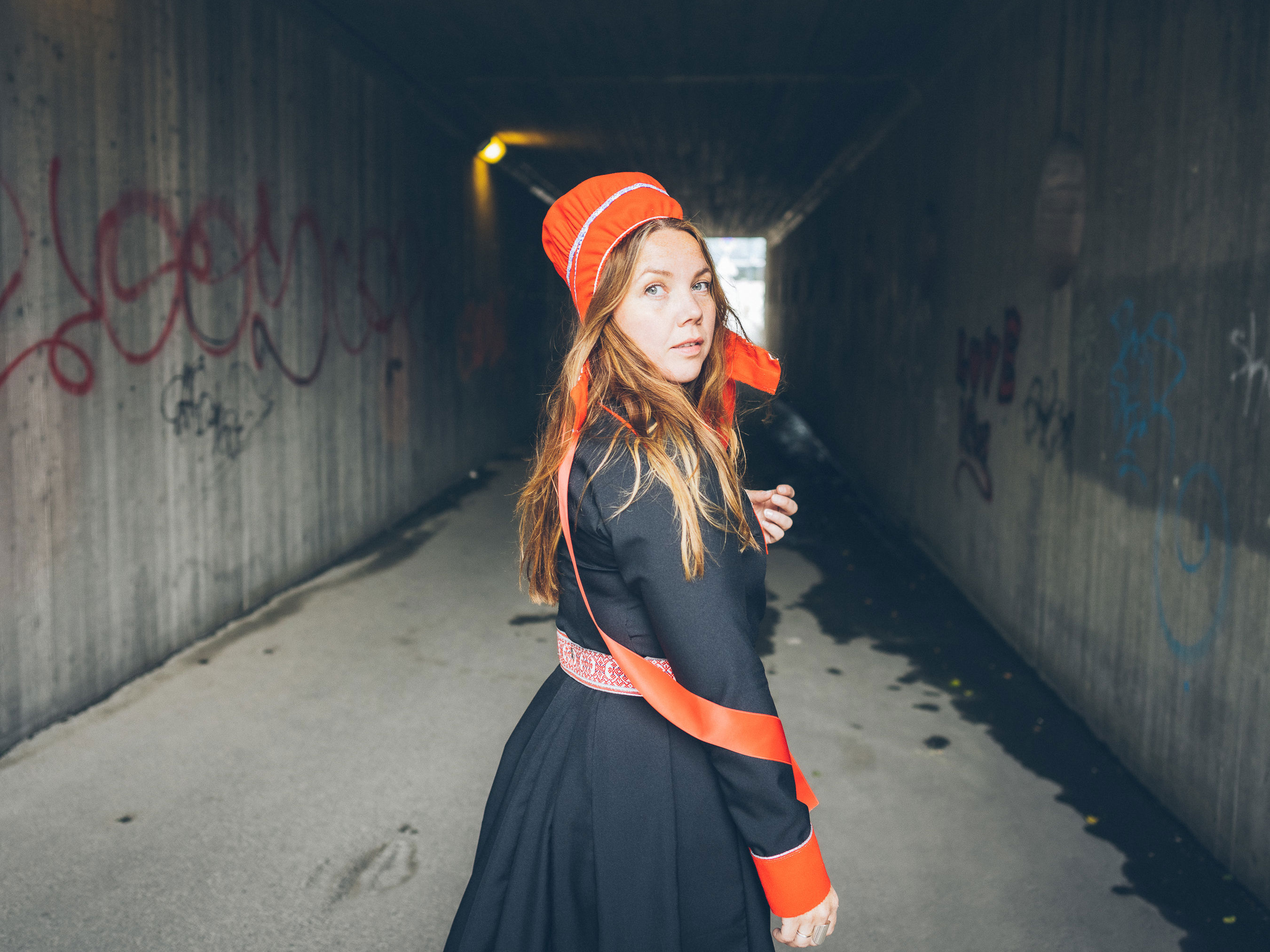 Halvkroppsbild på Kajsa stående inne i en gångtunnel iförd samiska kläder.